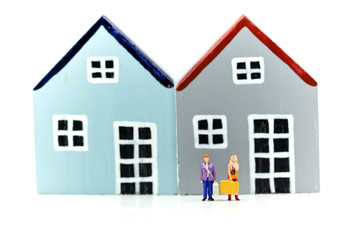 Obraz na płótnie Canvas Miniature people : Couple of love standing with Piggy bank with house and stack of coins,Saving to buy a house, real estate or home savings concept.