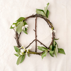 Peace sign, symbol of natural material - flowers, leaves, wooden sticks on tissue white background