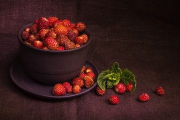Fresh strawberries in a bowl on brown cloth in a low key scene