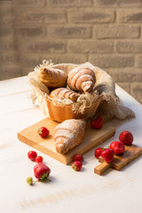 Delicious breakfast with fresh croissants and fresh berries on wooden background