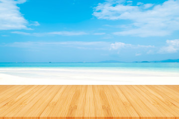 Fototapeta premium Perspective brown wooden table on top over blur sea in sunny day background. Beautiful sea and clouds in Thailand on summer, can be used mock up for montage products display or design layout.