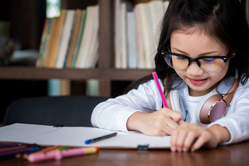 cute girl smiled and sitdown to drawing a book in the library, children concept, education concept