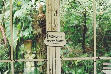 iron welcome to our home sign in glasshouse window background.