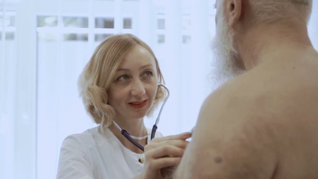 Smiling Doctor Listen Heart Of Eldelry Man With Stethoscope