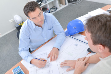 Two met sat at table discussing plans