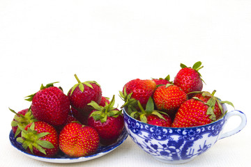 Fresh tasty red strawberry on a plate and a mug