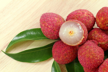 Fresh red lychee and peeled with leaves on wooden background with copy space. © Nattha99