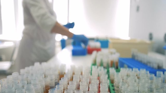 Samples are placed on a table, while a doctor works on a background. HD.