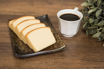 Homemade plain butter cake soft and moist. Slice of butter cake on plate and serve with black coffee on wooden background