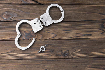 handcuffs for detaining criminals, key, on a wooden background. arrest, violation of the law.