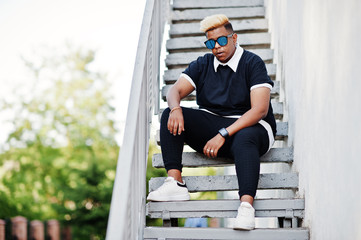 Stylish arabian muslim boy with originally hair and sunglasses posed on streets at ladder.