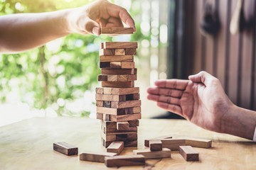 Hands of executive cooperation placing wood block on the tower, Collaborative management, Young...