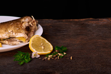 A slice of lemon with spices on a wooden background near white plate with fish