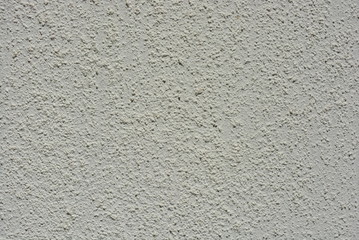 Spotted wall covered with special loose structure of building granules of white color in the sun