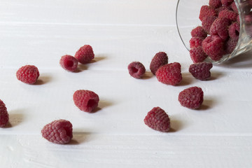 Ripe raspberry in a glass, on a white wooden table.