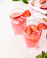 Glasses of a fresh pink lemonade. Strawberry soda with mint on a wooden table. 