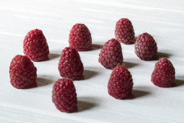 Ripe raspberries on a white wooden background.