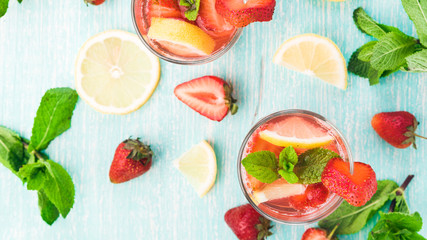 Glasses of a fresh pink lemonade. Strawberry soda with mint on a wooden table. 