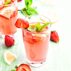 Glasses of a fresh pink lemonade. Strawberry soda with mint on a wooden table. 