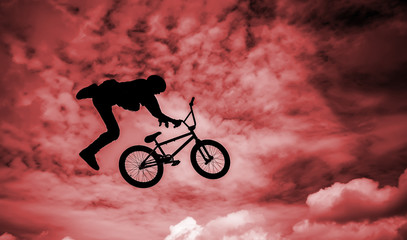Silhouette of a man doing an jump with a bmx bike.