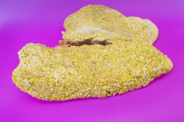 Meat schnitzel in breading close-up on a pink background