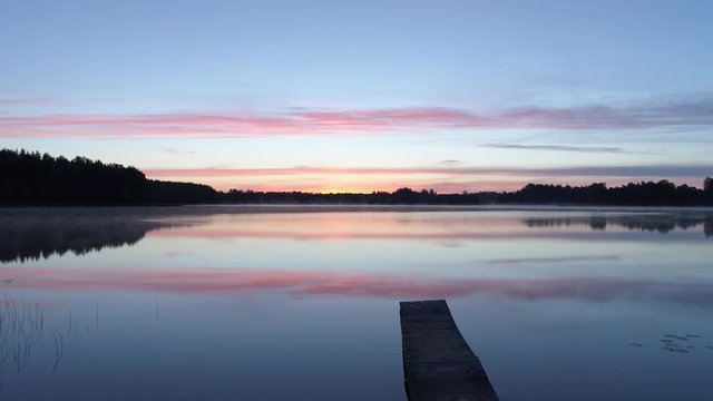Aerial shot of a wooden pier revealing a calm lake before sunrise in Latgale, Latvia