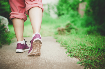 Woman legs walking. Step in sneakers.