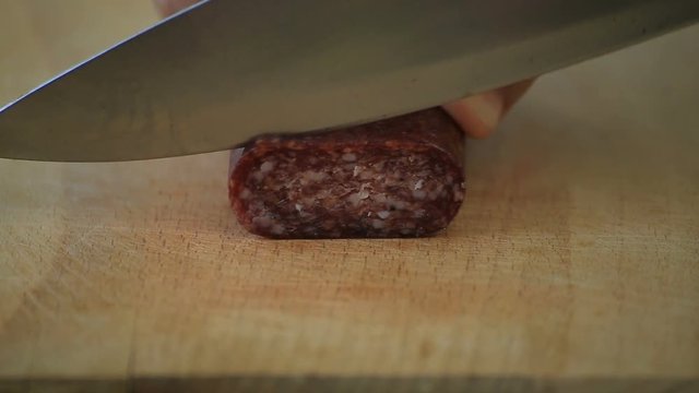 Closeup cutting bulgarian flat sausage called lukanka