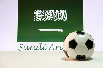 Small football on the white floor and Saudi Arabian nation flag with the text of Saudi Arabia background.