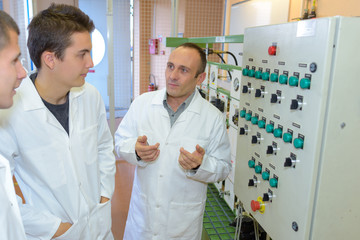 Man explaining control panel to male students