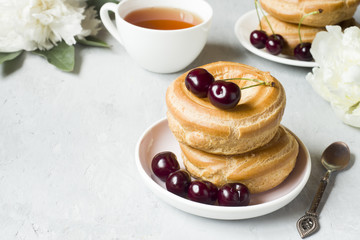 Custard cakes ring with cherry on a plate on a gray textured background. Selective focus. Copy space