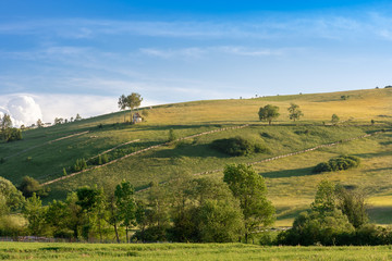 Fototapeta premium Tiny, picturesque chapel on a hill, among meadows and arable fields, a Polish village in the Pieniny