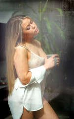 Obraz premium Sensual girl in nighdress drinking coffee at home in a raining day