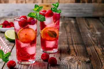 Raspberry Mojito Lemonade with lime and fresh mint in glass on wooden background