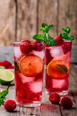 Raspberry Mojito Lemonade with lime and fresh mint in glass on wooden background