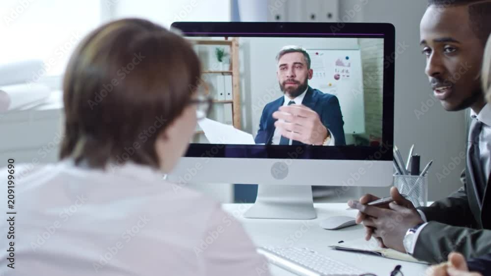 Poster tracking of mid-aged businessman showing documents at web cam and speaking with multiethnic team whi