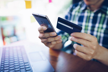 Man using mobile phone and laptop for shopping online by credit card. Pays for purchase.online shopping, online payment,buy and sell products & services.