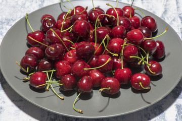 Obraz na płótnie Canvas Dark, ripe and juicy cherries on a black plate