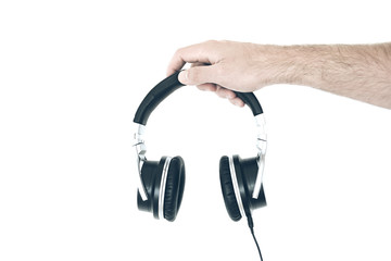 hand of man holding stereo headphones against white wall
