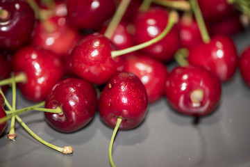 Dark, ripe and juicy cherries on a black plate