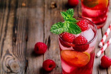 Raspberry Mojito Lemonade with lime and fresh mint in glass on wooden background