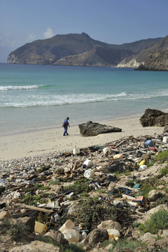Sultanate of OMAN, DHOFAR, a man is walking on a wild beach full of rubbish at the west of SALALAH