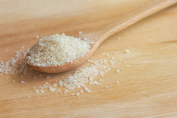 Natural brown sugar or no bleach sugar on wooden spoon put on wood table in side view with copy space. Sweet seasoning for good health concept. Ingredient prepared for cooking bakery and beverage.