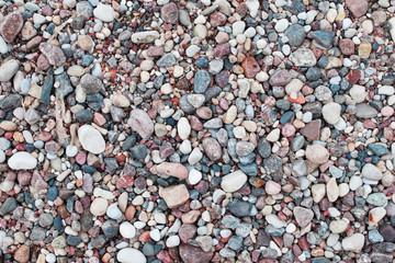 Different color, size and shape stone pebbles on seaside as natural abstract textured background.