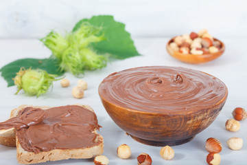 Homemade hazelnut spread in wooden bowl. Hazelnut Nougat cream on slice of bread