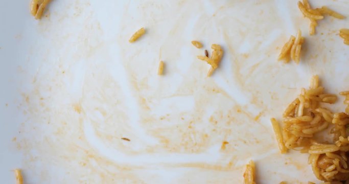 Top close view of using a fork to finish off a meal of spicy rice on a white plate.