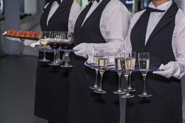 The waiter holds glasses of wine