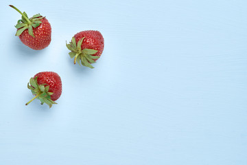 Food concept with sweet delicious strawberries on blue background, healthy organic food image, minimalistic fruit concept. top view.