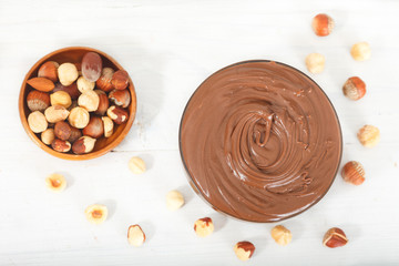 Homemade hazelnut spread with nuts on a white wooden table. Nutella cream, top view.