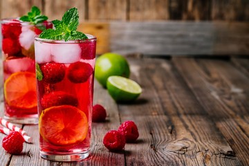 Raspberry Mojito Lemonade with lime and fresh mint in glass on wooden background